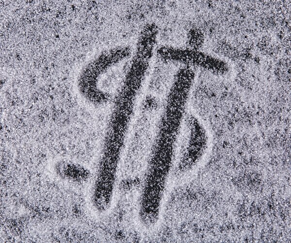 written by a finger dollar icon on the texture of white sugar crystals on the black background 