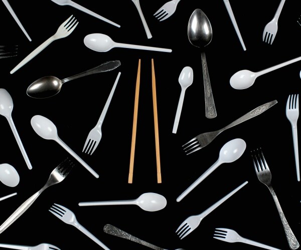 a variety of spoons, forks, chopsticks out on a table