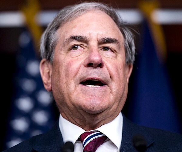 john yarmuth speaks to the media with an american flag in the background