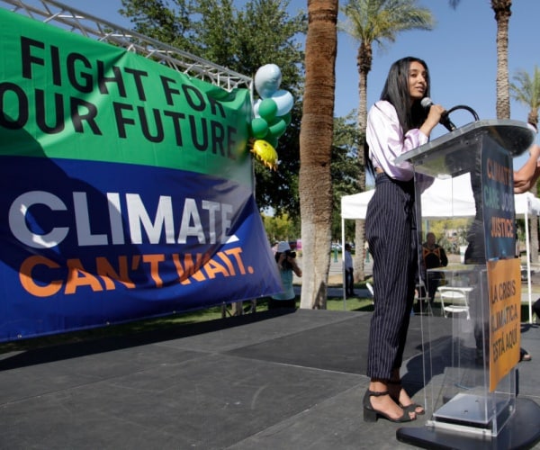 eco activist stands in front of podium with fight for our future slogans in background