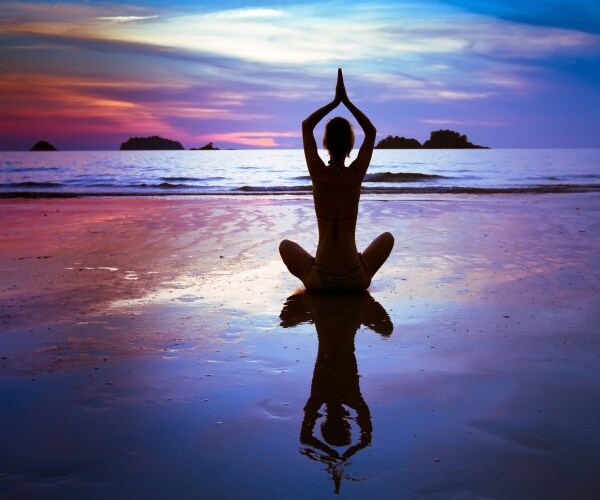 a person on beach in a yoga pose at sunset