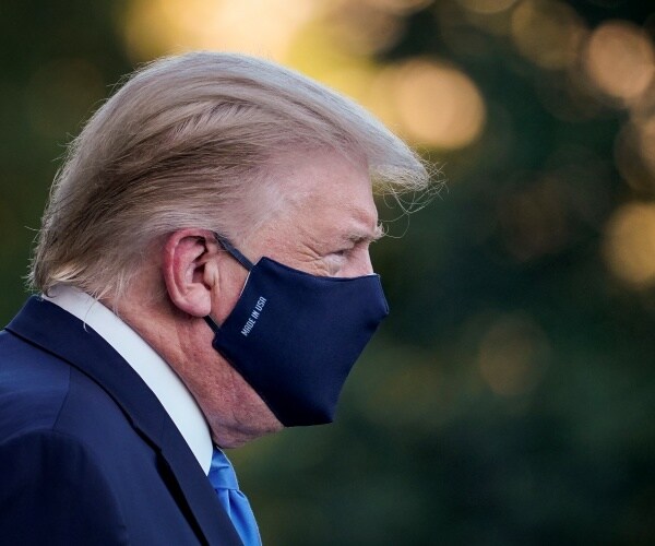 trump wearing a face mask standing outside