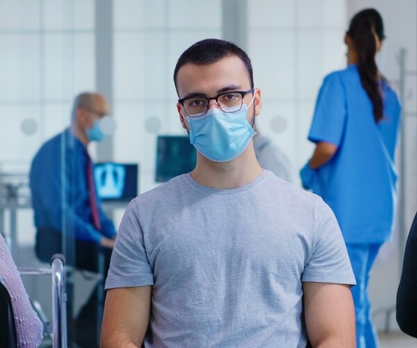 young man wearing mask in doctor's office waiting room