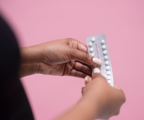 hands of woman holding birth control pills