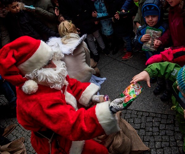 santa claus gives out wrapped gift to little boy