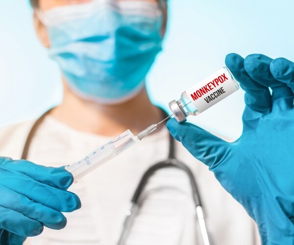 healthcare worker holding a vial of monkeypox vaccine and a syringe