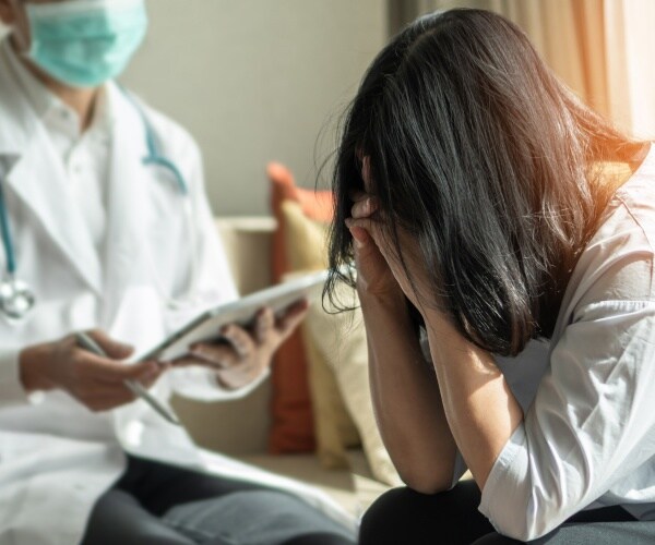 woman with head in her hands talking to doctor in office