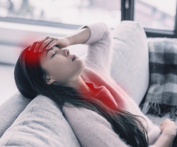 woman sitting on couch with head back with red showing pain in forehead, throat/chest