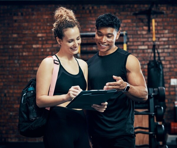 woman reviews fitness goals with a trainer in a gym