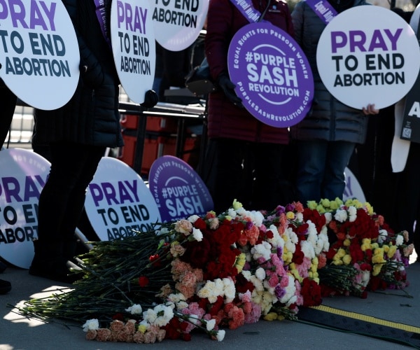 Roses that represent the number of abortions since the Roe v. Wade decision sit in front of activists