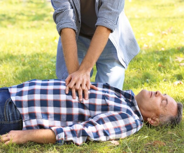 bystander performing CPR on man in park