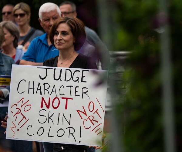 woman holds sign that says judge character not skin color