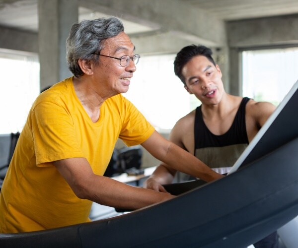 trainer helping older man use a treadmill