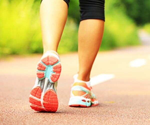 woman's bottom half/sneakers walking on path 