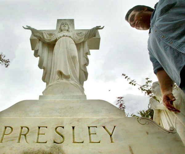 An Elvis fan views the Presley family headstone at Graceland where Elvis Presley is buried. 