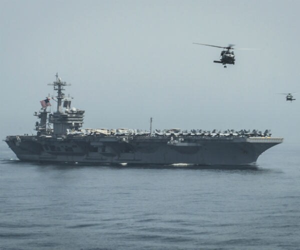 the uss theodore roosevelt is shown with two helicopters hovering above it 