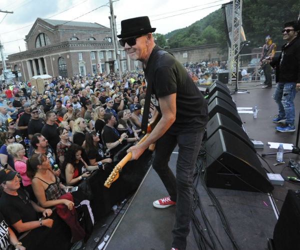 the great white band members are seen performing with guitar player out from in all black attire and red chucks