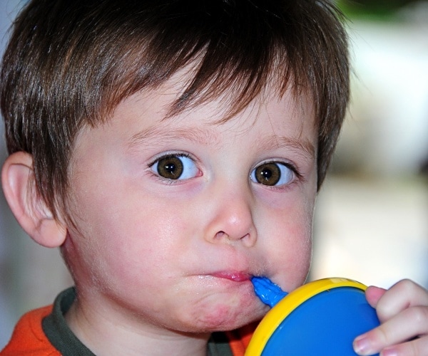 child drinking from straw cup