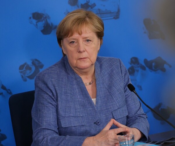 angela merkel sits at table 