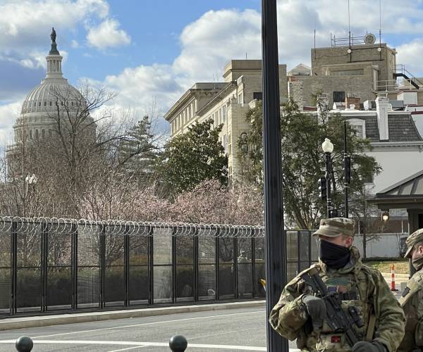 the capitol building with fencing and national guard members