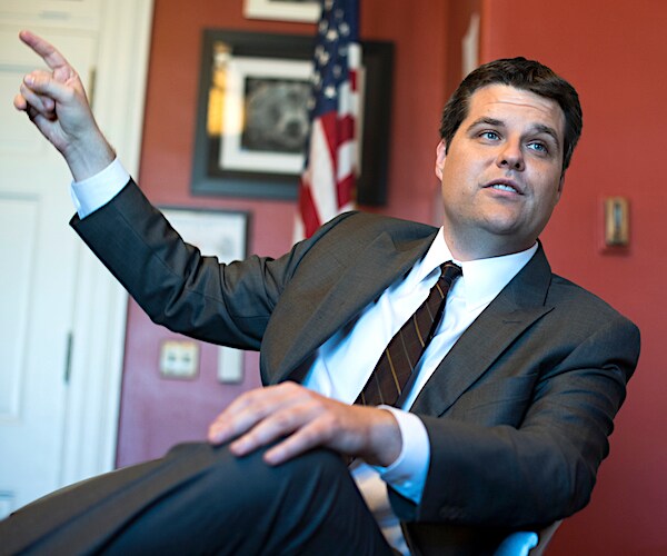 republican representative matt gaetz sits and points upward with his right index finger