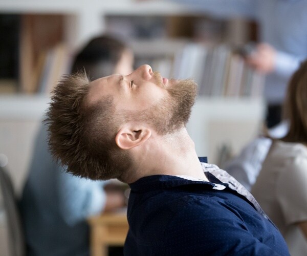 man's head back in chair, asleep at work