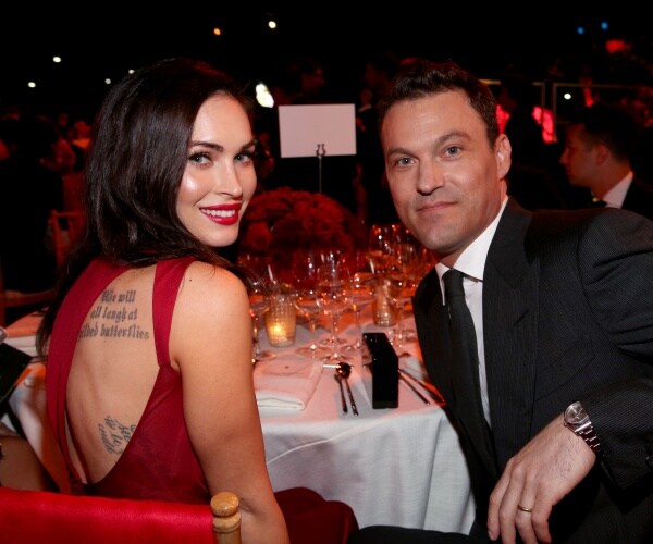 megan fox in a red dress sitting at a dinner table with brian austin green in a black suit and tie