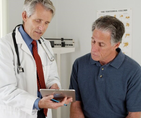 physician talking to patient, looking at iPad together