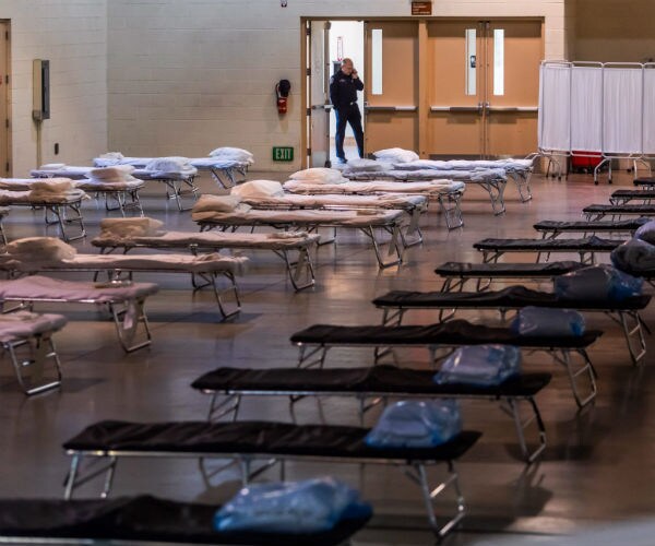 a temporary hospital setting is shown with rows and rows of empty beds