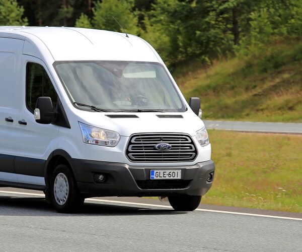 white ford transit drives down highway