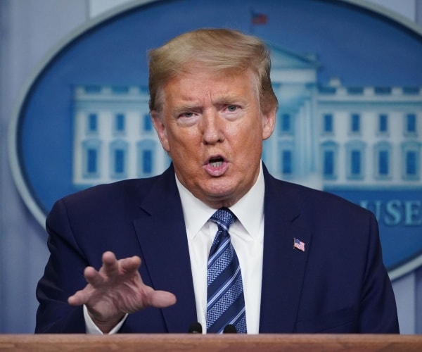 trump in a navy blue suit and blue striped tie in the press briefing room