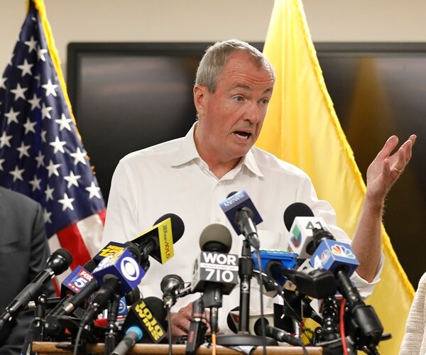 gov. phil murphy speaks from a podium with many mics on it