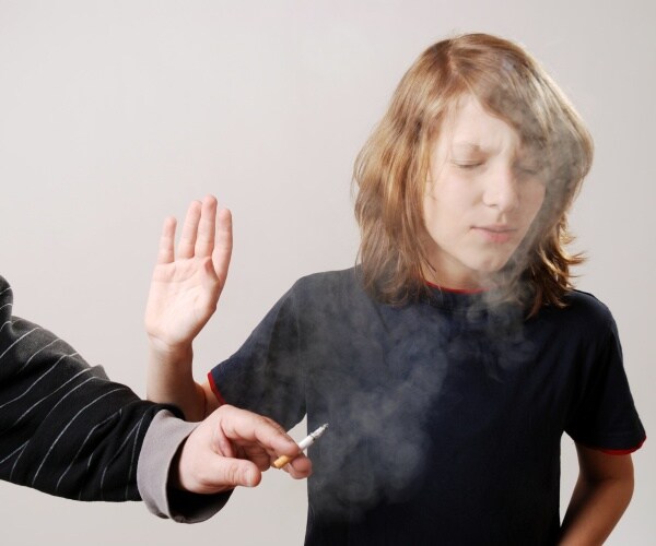 young boy waving away secondhand smoke from a parent smoking