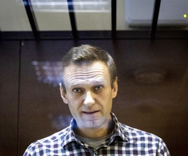 alexei navalny stands behind a glass in a prison