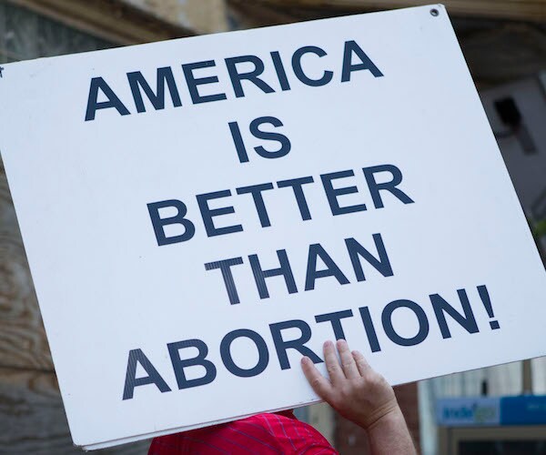 a protester's sign reads america is better than abortion