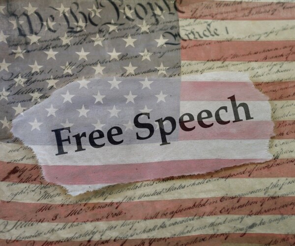 free speech news headline on a copy of the us constitution and the us flag