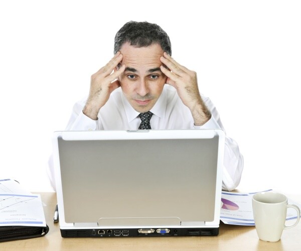 man looking stressed out sitting at desk at work