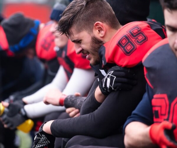 football player in pain on bench