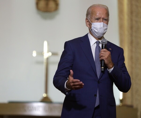 biden in a suit and purple speaking at a church 