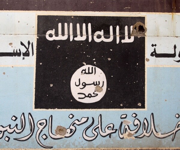 mural depicting isis flag is shown in front of other arabic lettering on a blue and white background