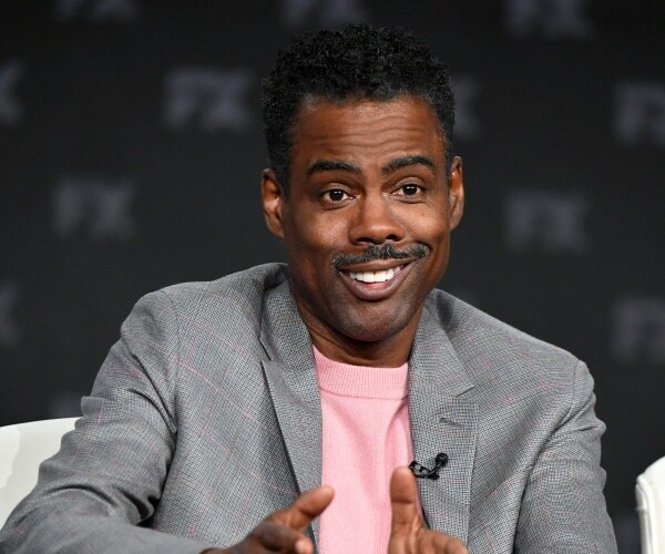 chris rock in a gray blazer and pink shirt