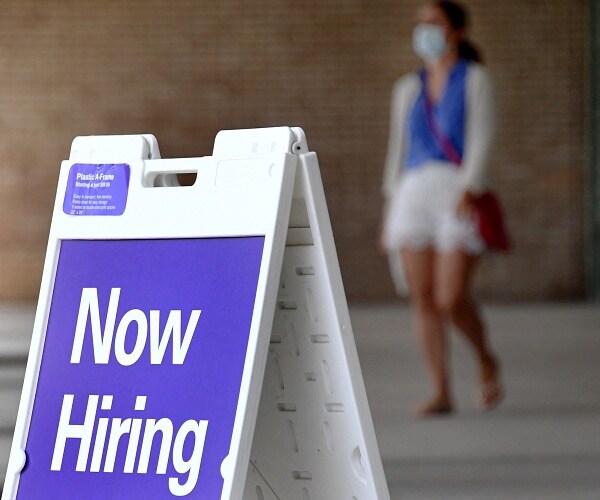 now hiring sign stands outside business