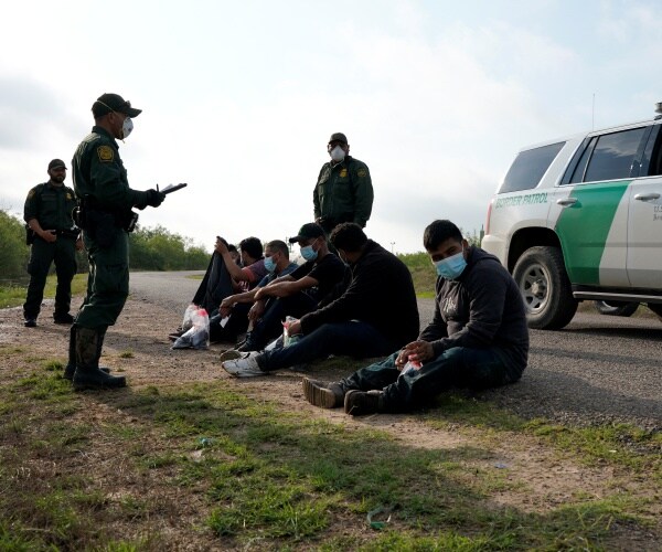 Undocumented migrants are detained by Border Patrol along a road.