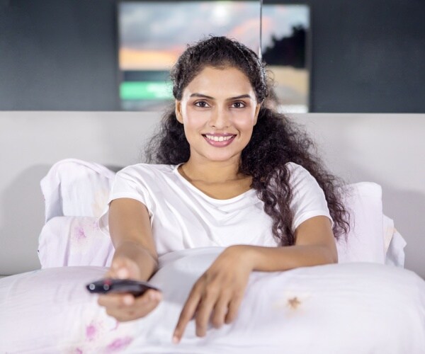 woman in bed watching tv