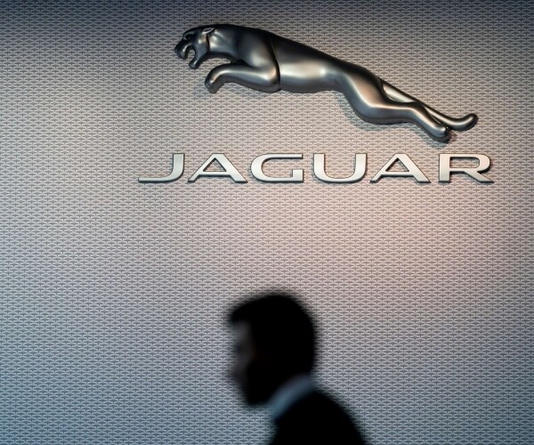 jaguar logo is shown on the wall with a man walking by