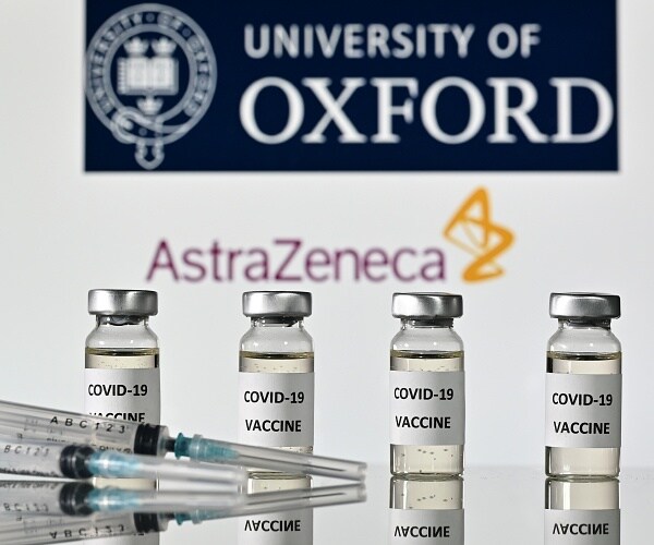 vials of coronavirus vaccine and syringes in front of astrazeneca logo