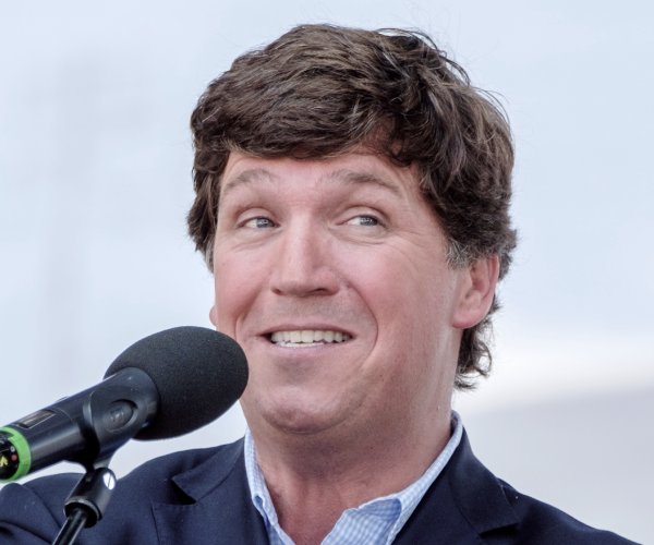 Tucker Carlson looks on.