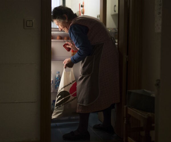 older woman cleaning food out of refrigerator