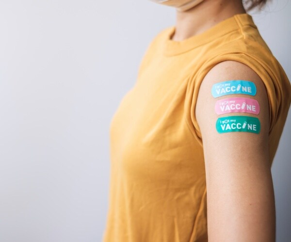 woman's arm with three band-aids that say "I got my vaccine"