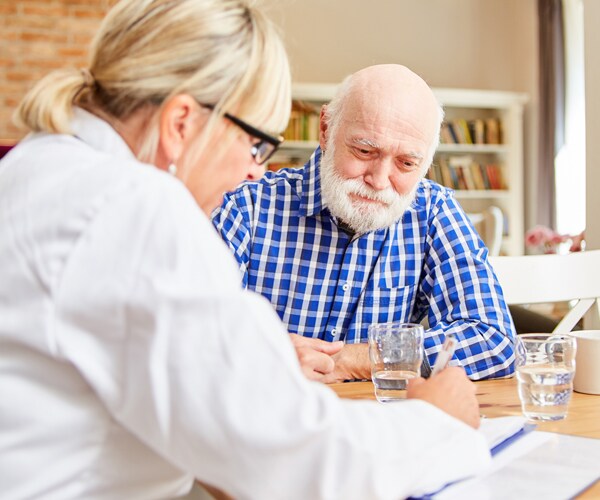 a doctor talks with a patient during a home visit